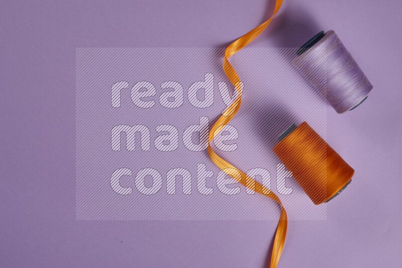 An orange collection of sewing and tailoring tools arranged on a purple background