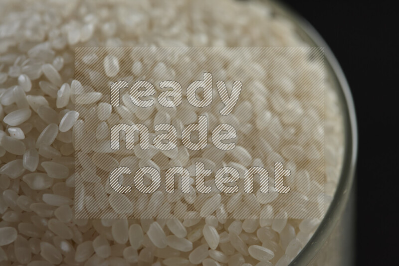 White rice in a glass jar on black background