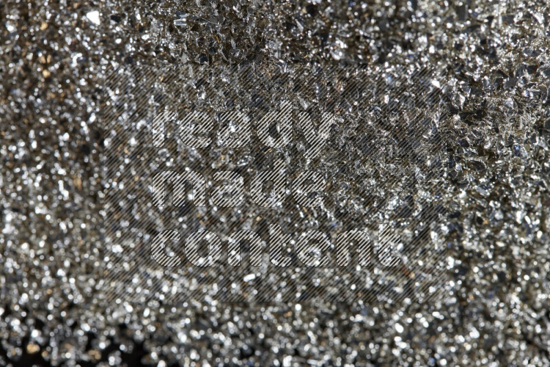 Silver shimmering fragments of glass scattered on a black background