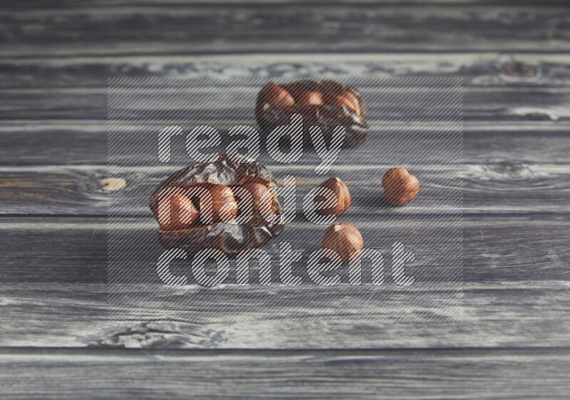 two hazelnut stuffed madjoul dates on a wooden grey background