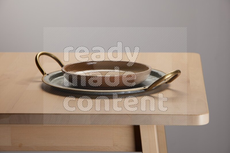 multicolored plate placed on a rounded stainless steel tray with golden handels on the edge of wooden table