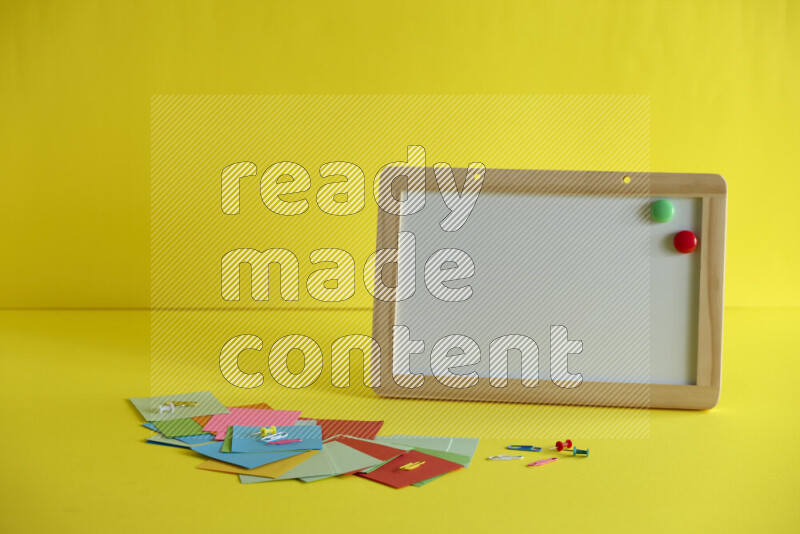 سبورة بيضاء مع لوازم مدرسية مختلفة على خلفية صفراء