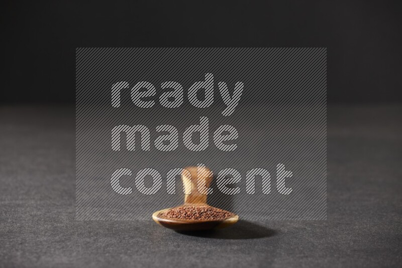 ملعقة خشبية كبيرة ممتلئة ببذور حب الرشاد علي خلفية سوداء