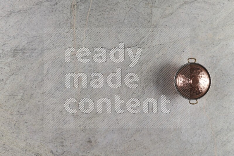 A small copper pot on grey marble background