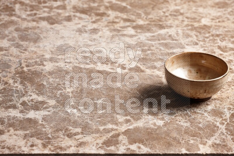A beige pottery bowl on beige marble background