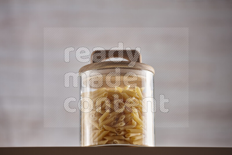 Raw pasta in glass jars on beige background