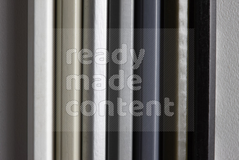 A collection of colored pencils arranged showcasing a gradient of white, grey and black hues on grey background