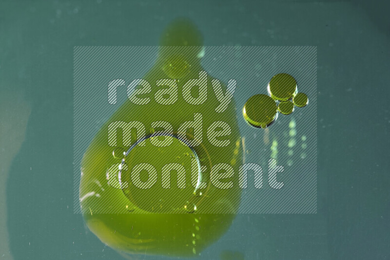 لقطات مقربة لقطرات ألوان مائية صفراء على سطح الزيت على خلفية خضراء