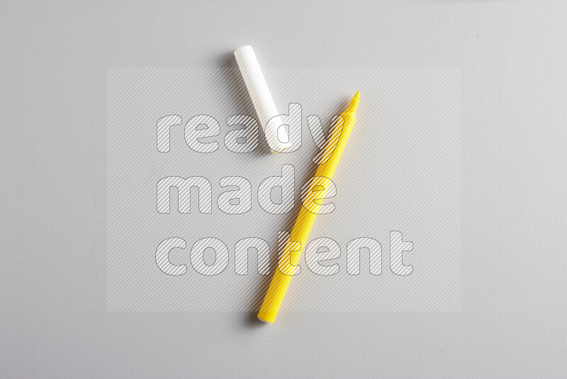 A close-up showing an open single coloring pen with a cap on grey background