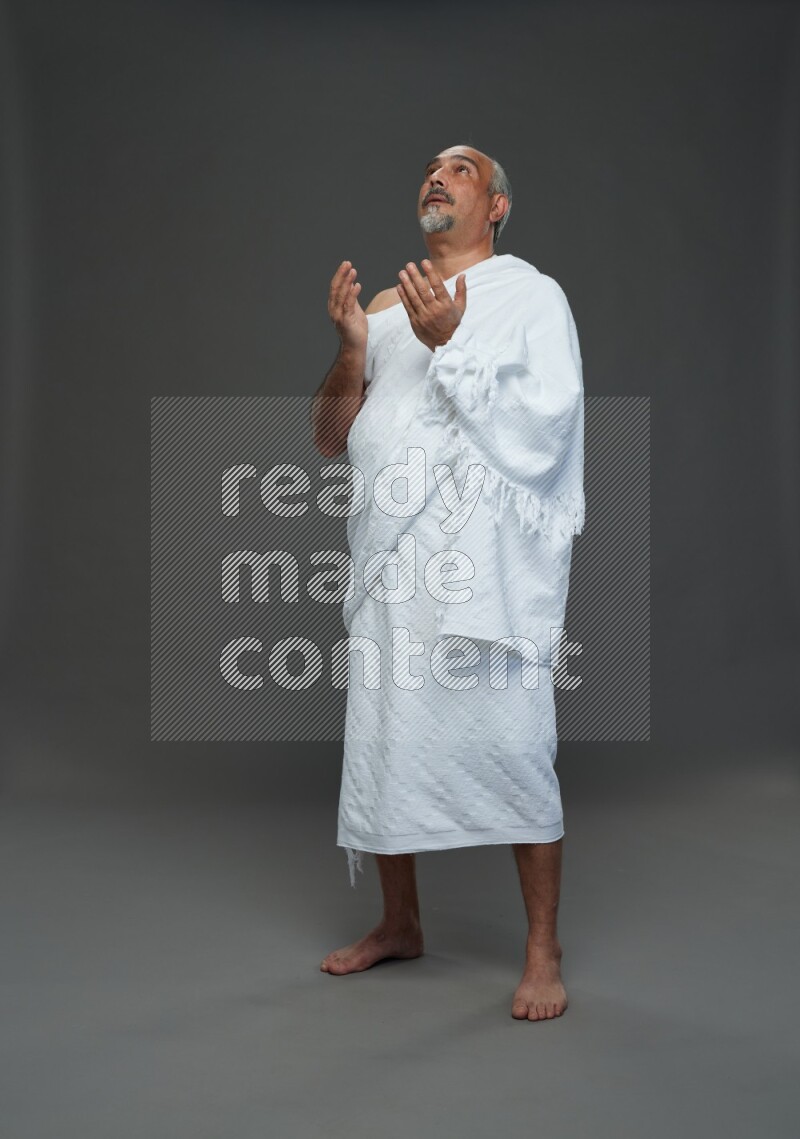 A man wearing Ehram Standing dua'a on gray background