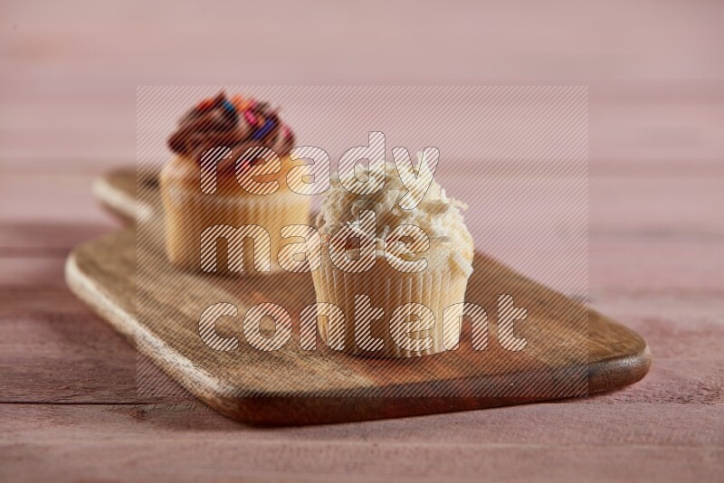 Vanilla mini cupcake topped with coconut on a wooden board