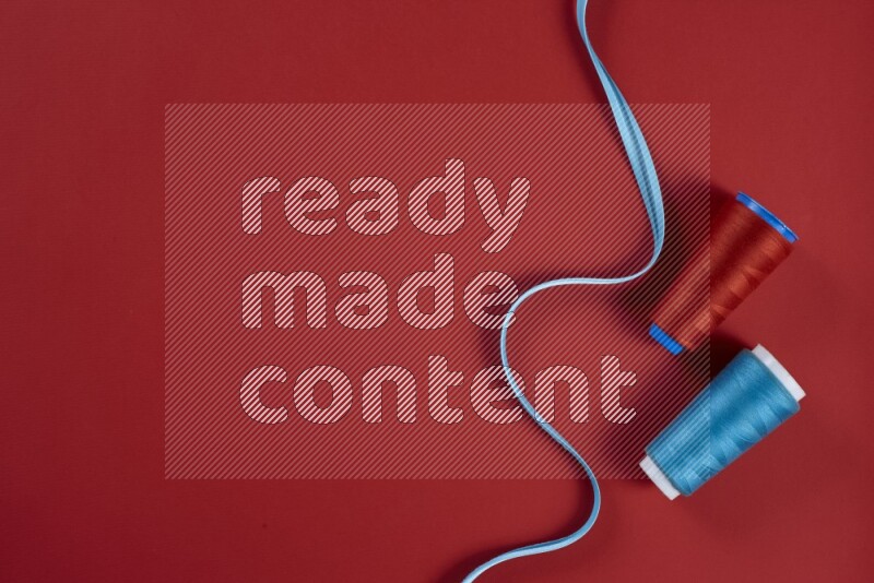 A blue and red collection of sewing and tailoring tools arranged on a red background