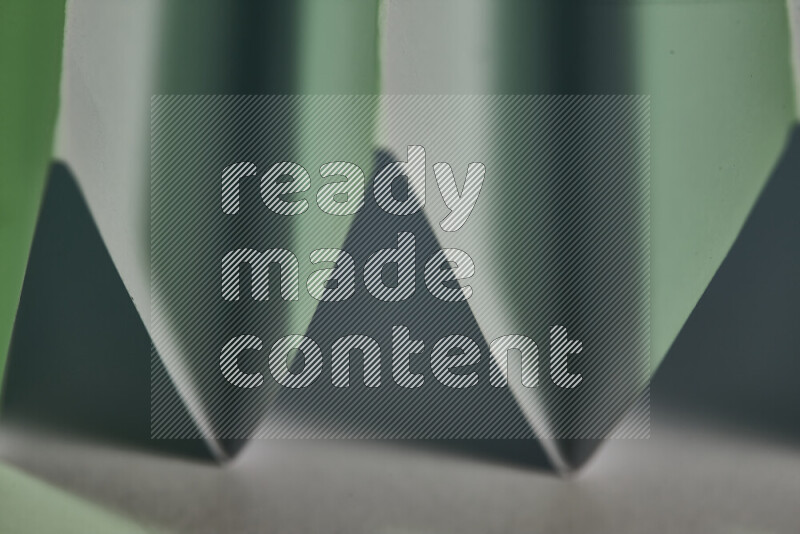 A close-up abstract image showing sharp geometric paper folds in white and green gradients