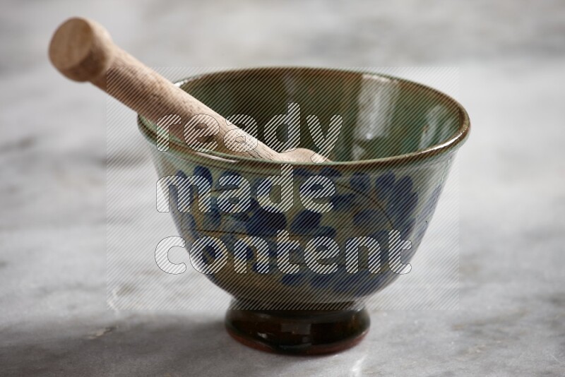 Decorative pottery bowl with wooden honey dipper in it on grey marble background