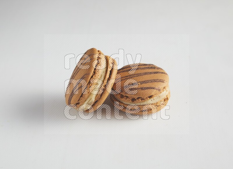 45º Shot of two light brown  Almond Cream macarons on white background