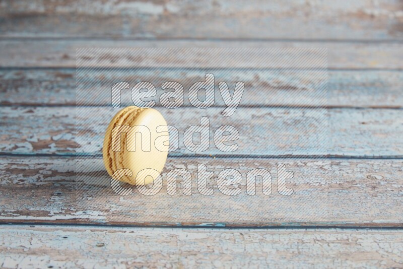 45º Shot of Yellow Vanilla macaron on light blue wooden background