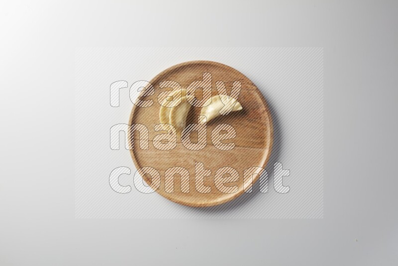 Three Sambosas on a wooden round plate on a white background