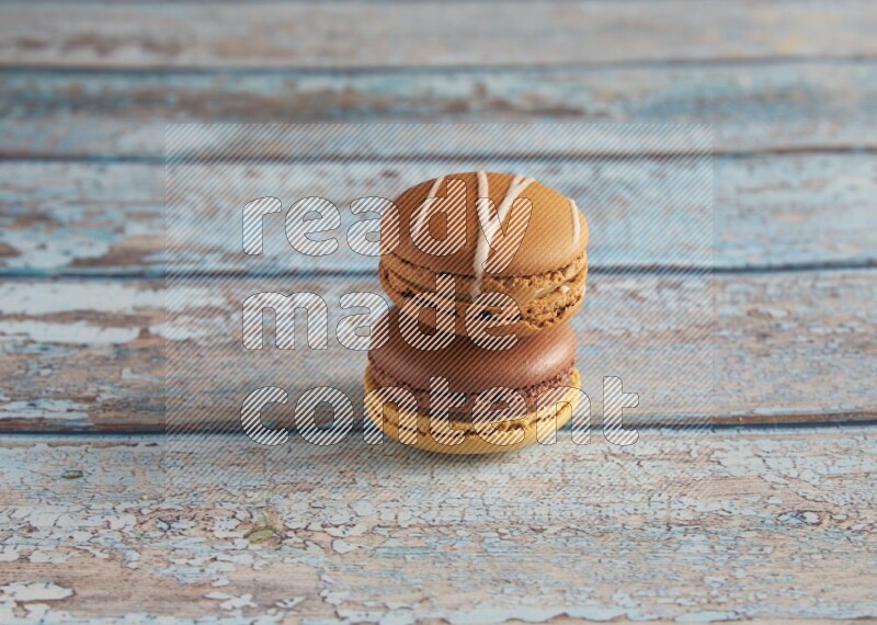 45º Shot of of two assorted Brown Irish Cream, and Yellow, and Brown Chai Latte macarons  on light blue background