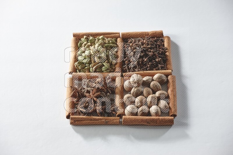 4 squares of cinnamon sticks full of cardamom, star anise, cloves and nutmeg on white flooring