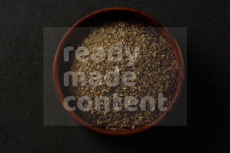 wooden round sauce bowl filled with herbs on grey textured countertop