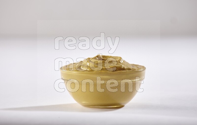 A glass bowl full of mustard paste on a white flooring