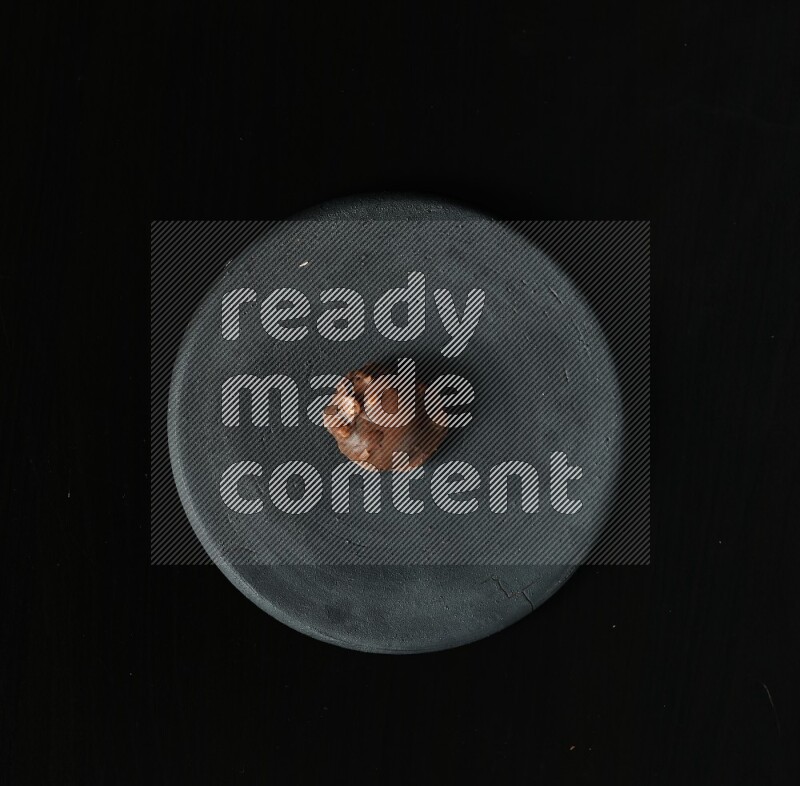 Assorted desserts in a black pottery plate on black background