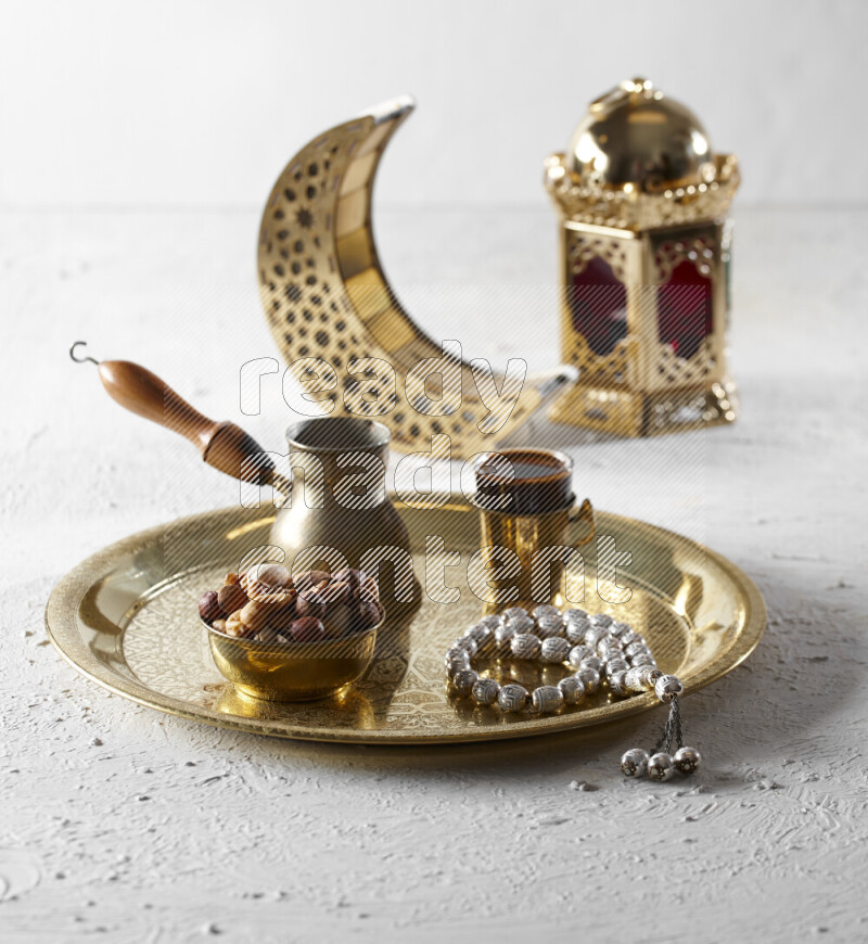 مكسرات في وعاء معدني مع قهوة وسبحة على صينية بجانب فوانيس علي خلفية بيضاء