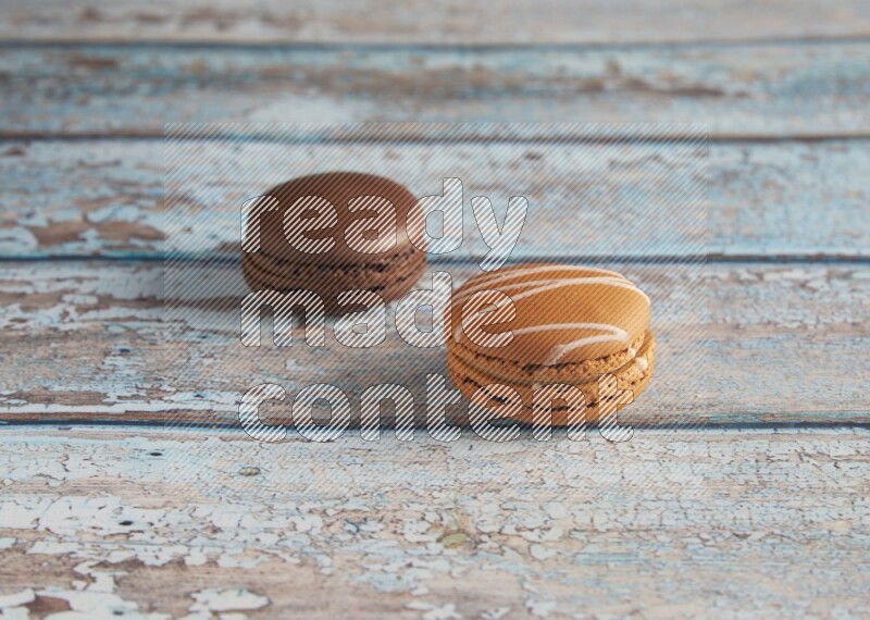 45º Shot of of two assorted Brown Irish Cream, and Brown Dark Chocolate macarons on light blue background