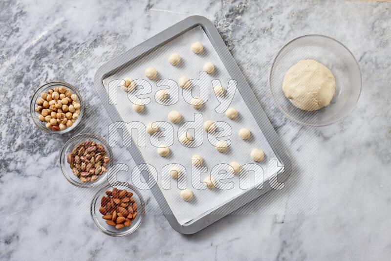 Ghoriba step by step with its ingredient, flour, powdered sugar, ghee and nuts on grey marble background