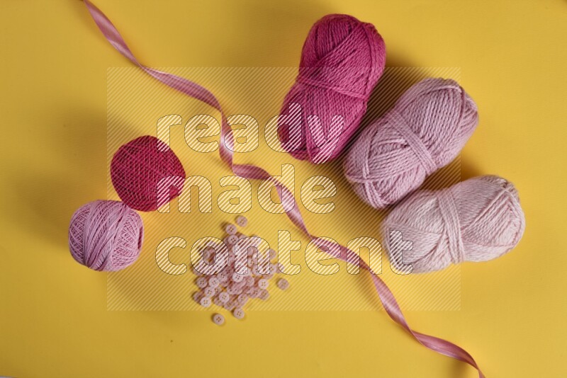 A pink collection of sewing and tailoring tools arranged on a yellow background