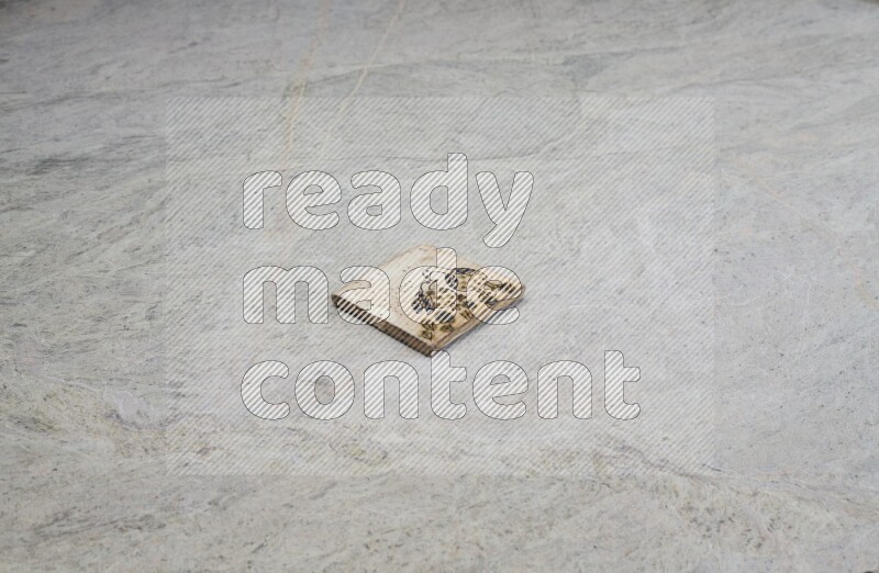Top view shot of a pottery coaster\ tile on beige marble flooring
