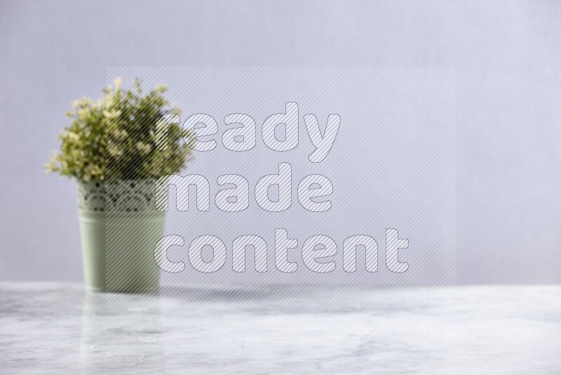 Artificial plant in green decorative pot on grey marble background