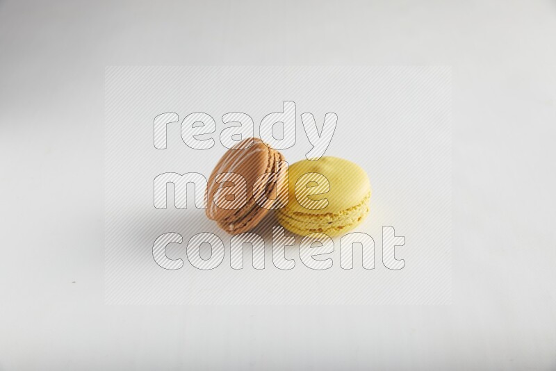 45º Shot of of two assorted Brown Irish Cream, and Yellow Lemon macarons on white background