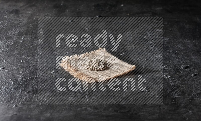 حبوب الفلفل الأبيض على قطعة من الخيش فوق أرضية سوداء