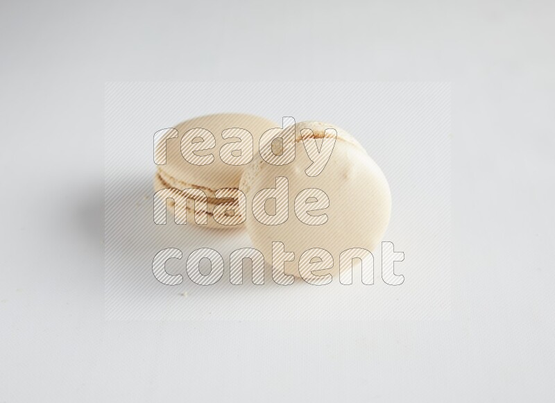 45º Shot of two White Caramel fleur de sel macarons on white background
