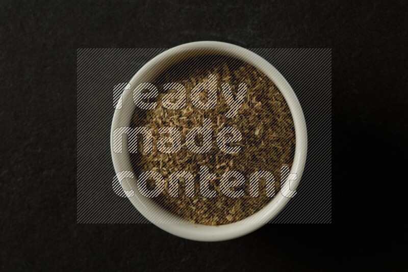wooden round sauce bowl filled with herbs on grey textured countertop