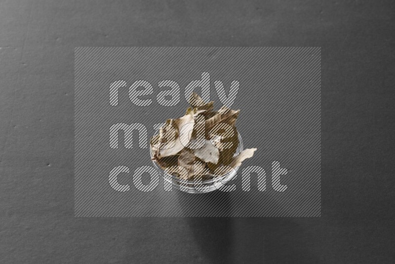A glass bowl full of laurel leaves on black flooring