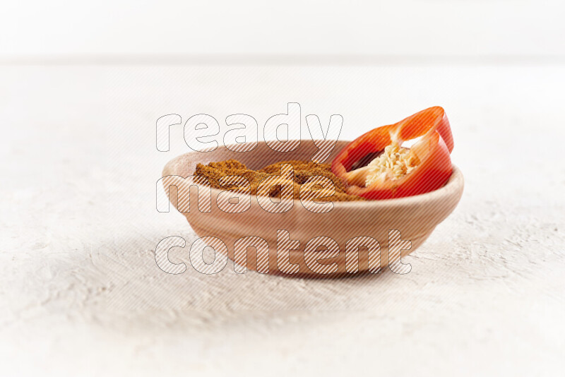 A wooden bowl full of ground paprika powder on white background