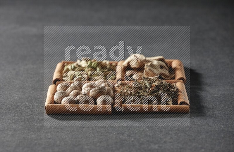 4 squares of cinnamon sticks full of dried basil, cardamom, dried ginger and nutmegs on black flooring
