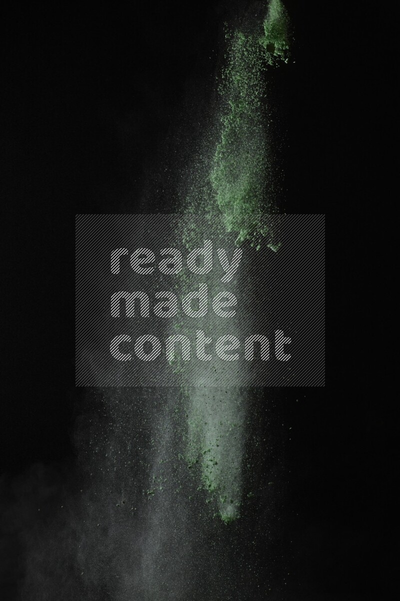 A side view of green powder explosion on black background