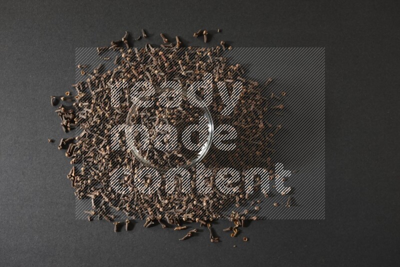 A glass bowl full of cloves on a black flooring