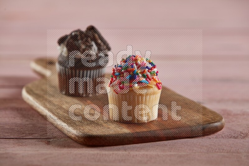 Vanilla mini cupcake topped with sprinkles on a wooden board
