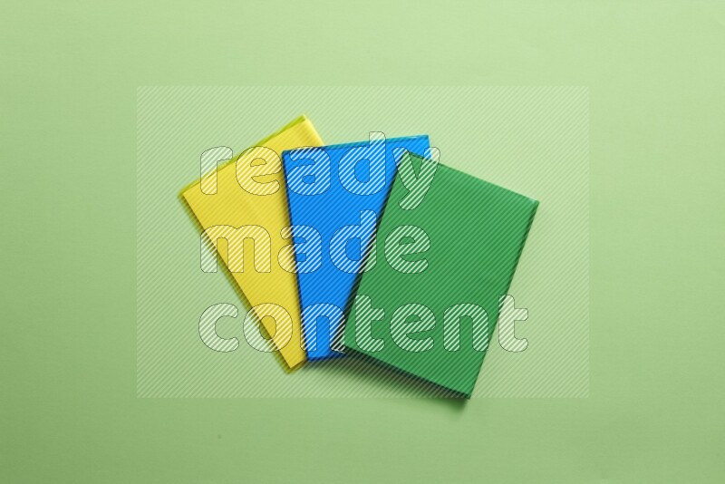 Multicolored notebooks on green background