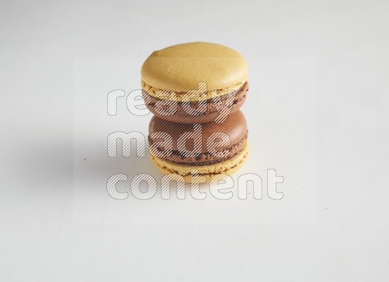 45º Shot of two Yellow and Brown Chai Latte macarons on white background