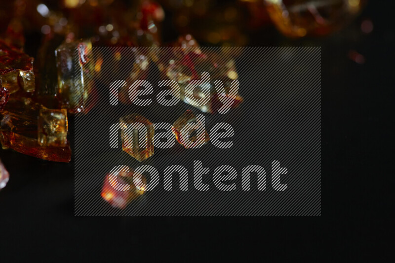 Transparent orange fragments of glass scattered on a black background