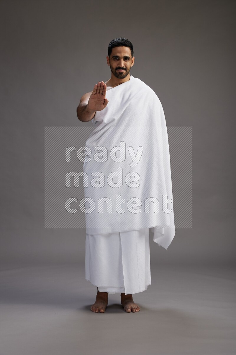 A man wearing Ehram Standing Interacting with the camera on gray background
