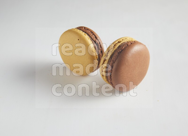 45º Shot of two Yellow and Brown Chai Latte macarons on white background