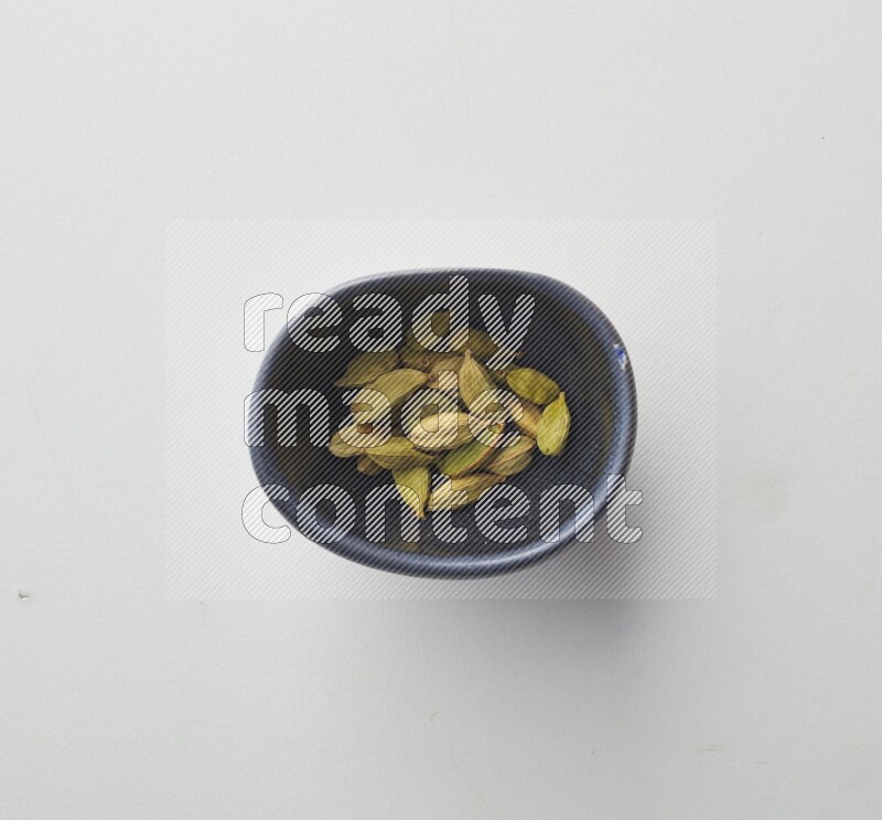 Top-view shot of Cardamon in a container on white background
