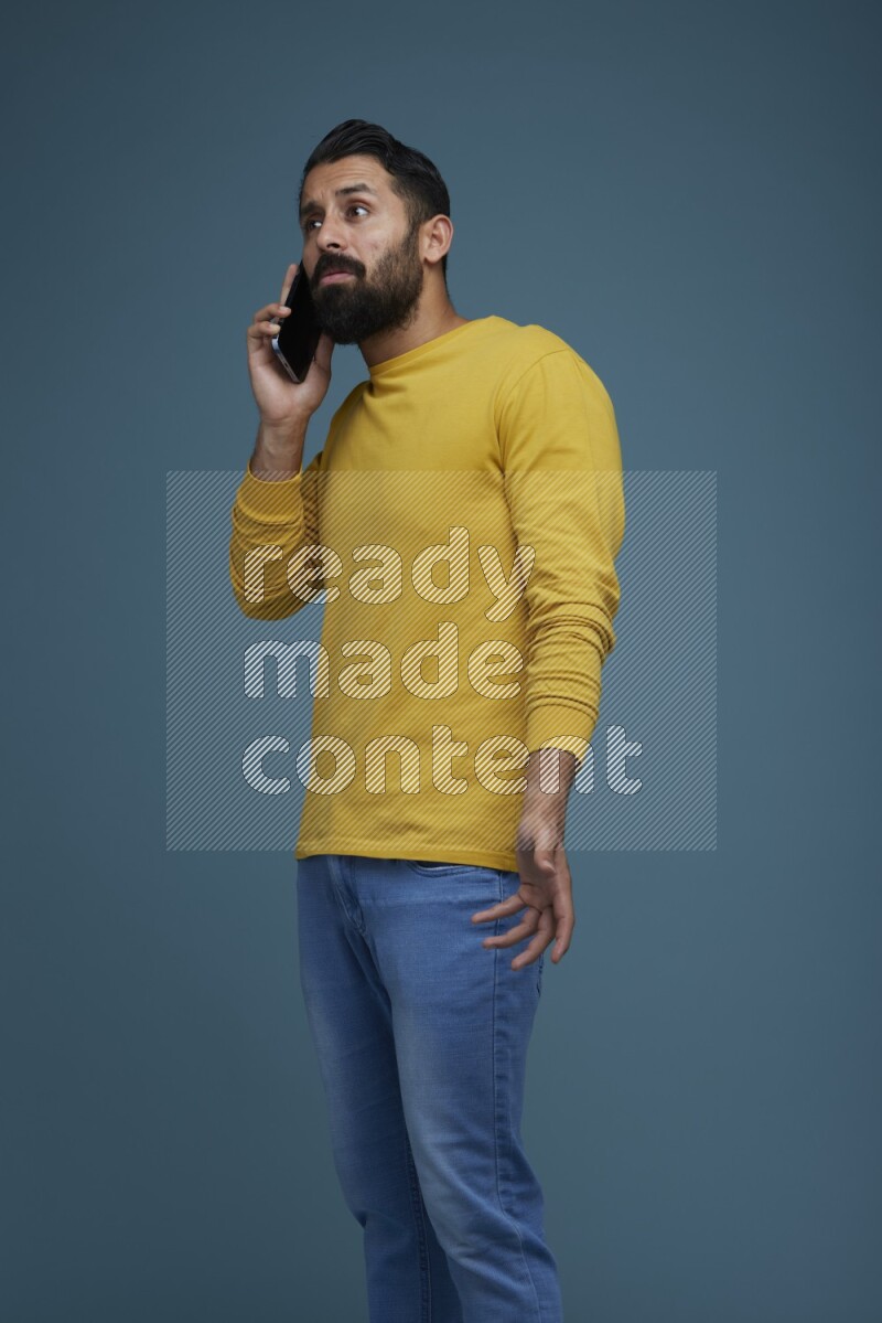 A man having a calling in a blue background wearing a yellow shirt