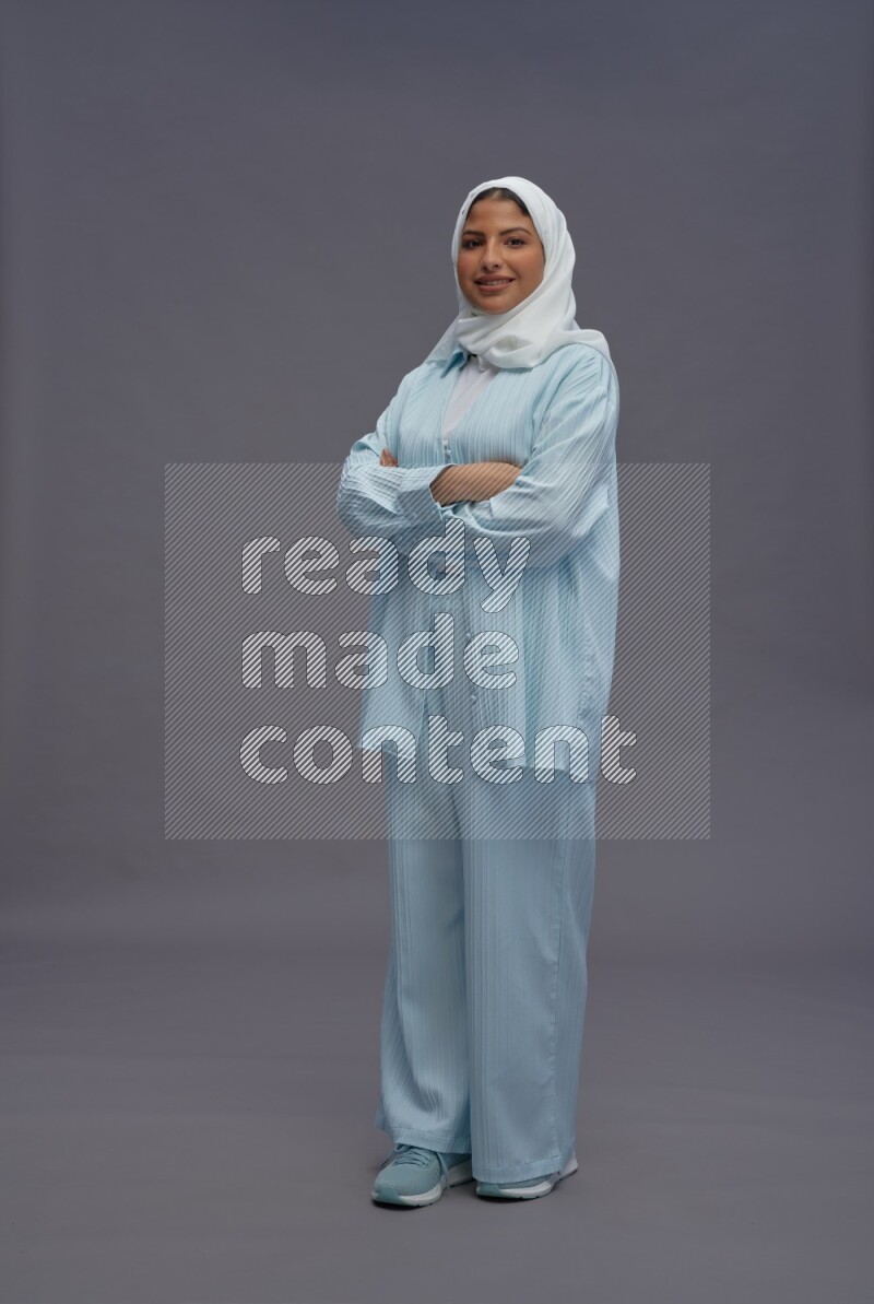 Saudi woman wearing hijab clothes standing with crossed arms on gray background